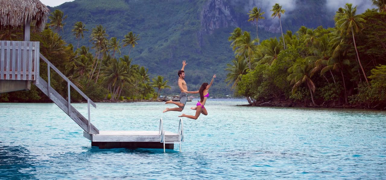 Couple jumping into the waters of Bora Bora - Tahiti Tourisme